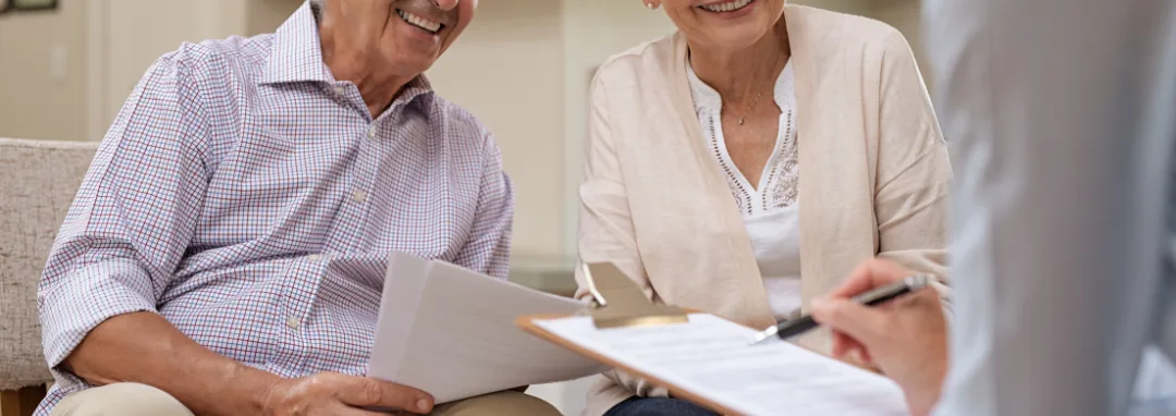 Smiling older couple reviewing paperwork with an adviser